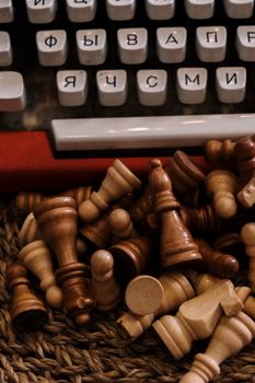 特写镜头中，散落的棋子旁是一台带有西里尔字母键的老式打字机