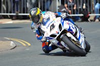 专业摩托车赛车手在户外赛道上高速行驶时，精准地通过急转弯