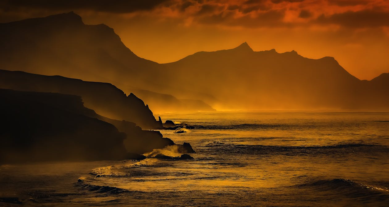 Silhouette of a Shore and Mountain View During Golden Hour