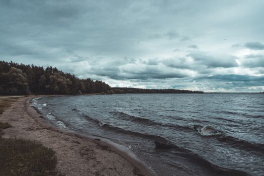 Tranquil shoreline with waves under a moody, cloudy sky capturing nature's serene beauty.