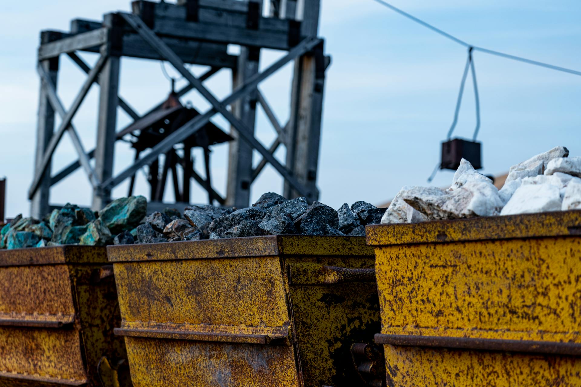 Detailed view of rusty mining equipment loaded with rocks under a clear sky.