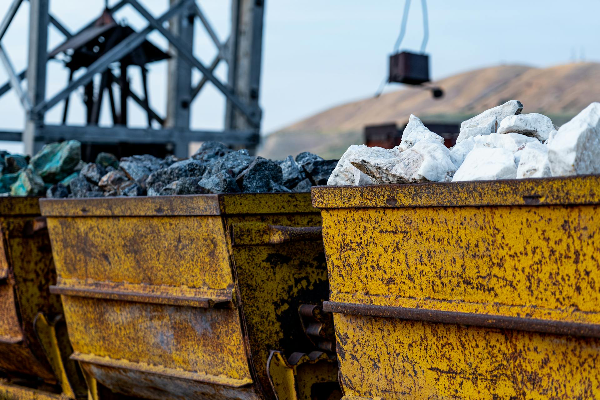 Close-up of rusty mining carts filled with various minerals in an industrial setting.