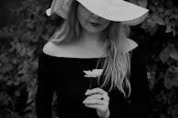 戴着帽子的黑白雌性作物温柔地匿身在灌木丛中，花朵盛开