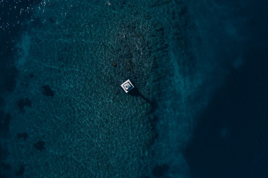 Stunning aerial capture of a solitary lighthouse on the Croatian coast surrounded by deep blue waters.
