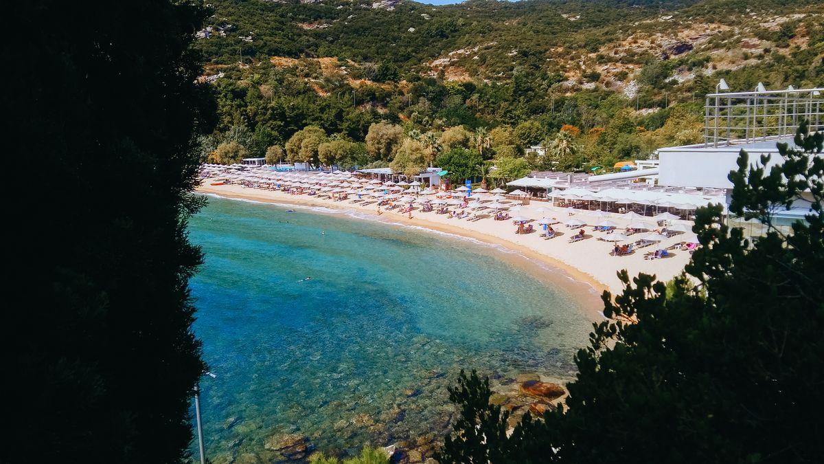 Golf din Halkidiki cu plajă de nisip, umbrele și vegetație verde care coboară spre apă