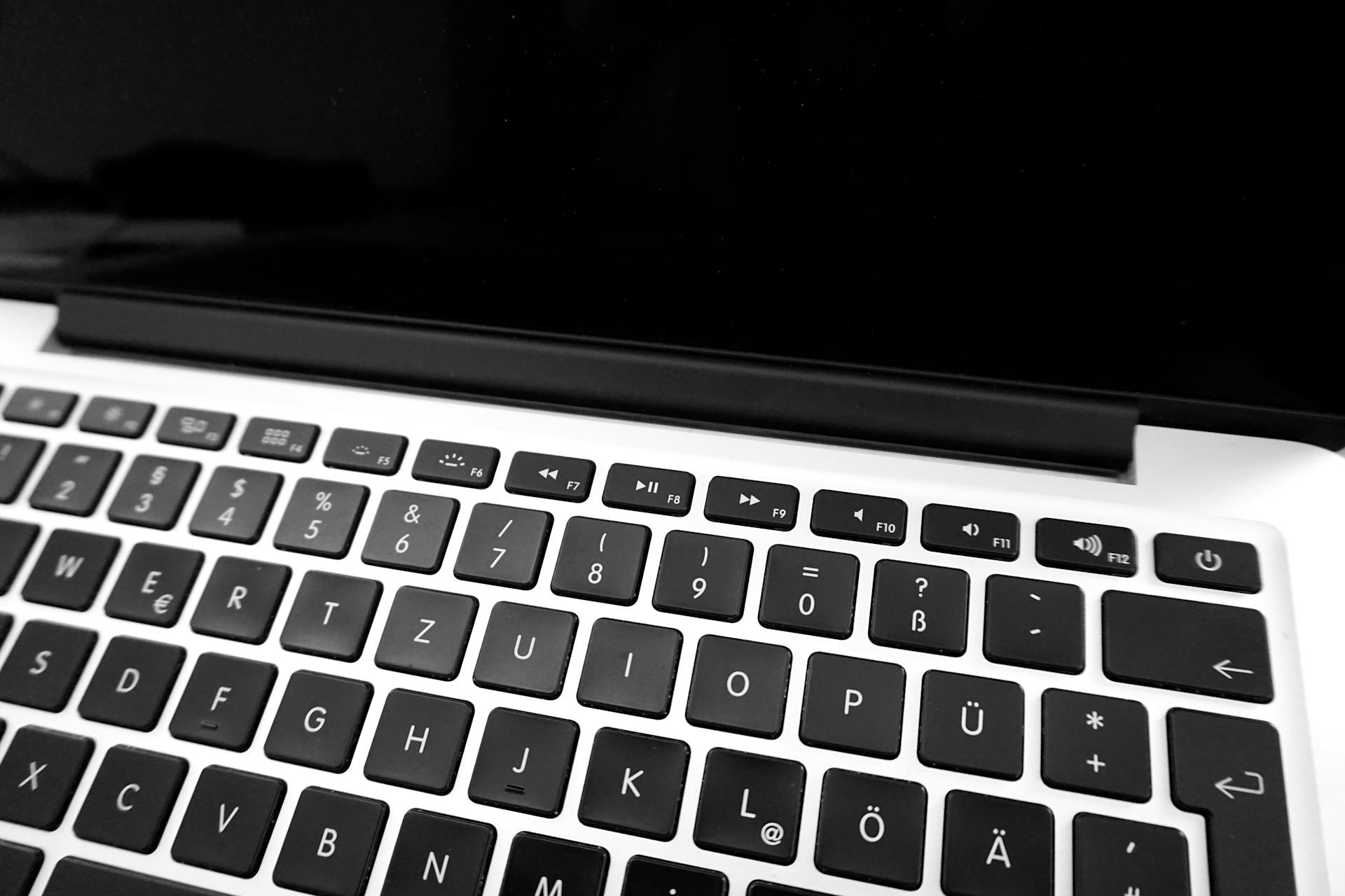 Monochrome image of a laptop keyboard showing German layout keys close-up.