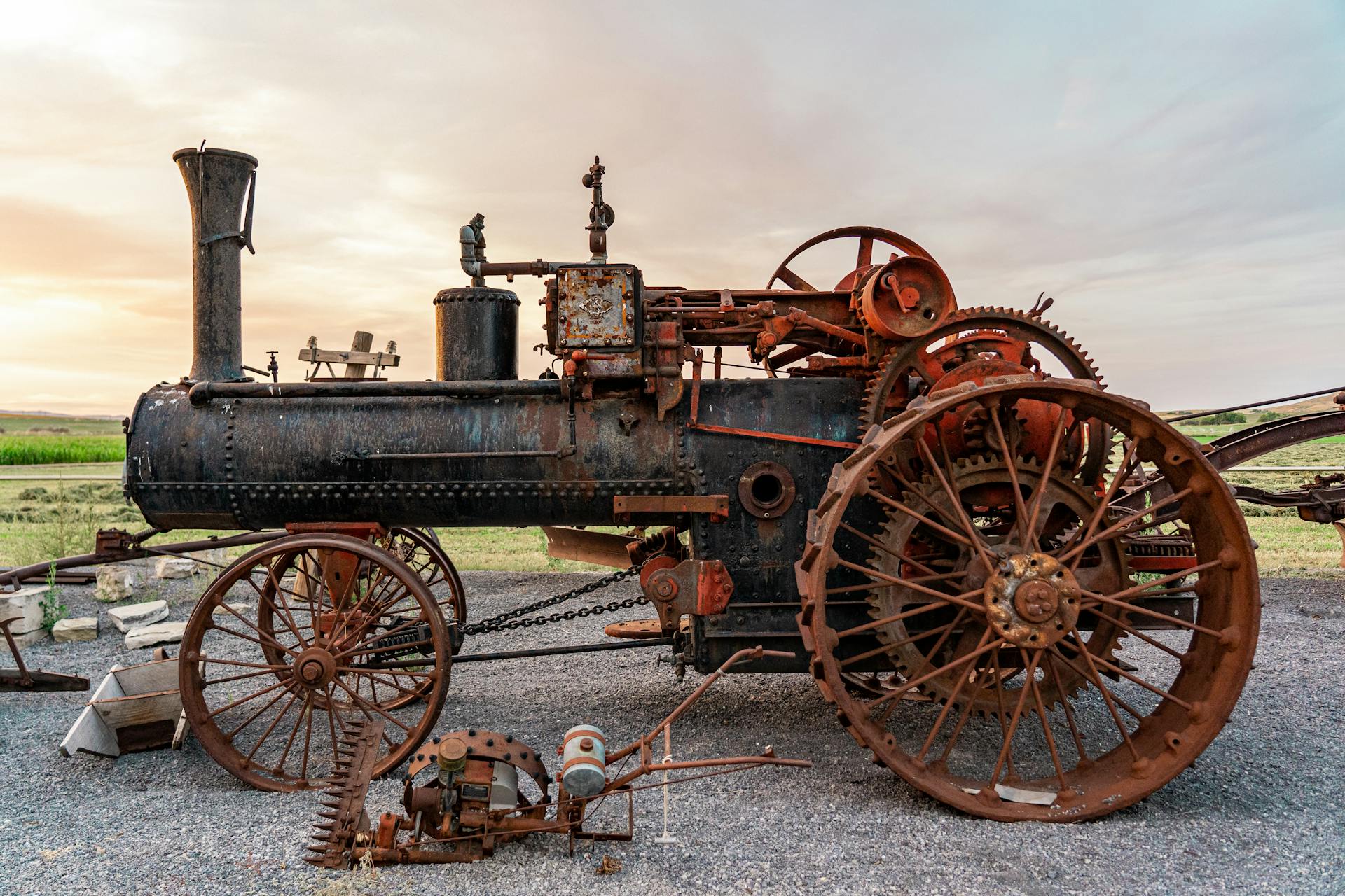 Antique metal steam traction engine with rust and wheels in an open field. Outdoor machinery photography.