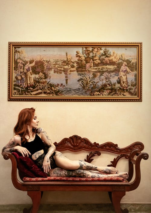 Tattooed woman lying on sofa under picture