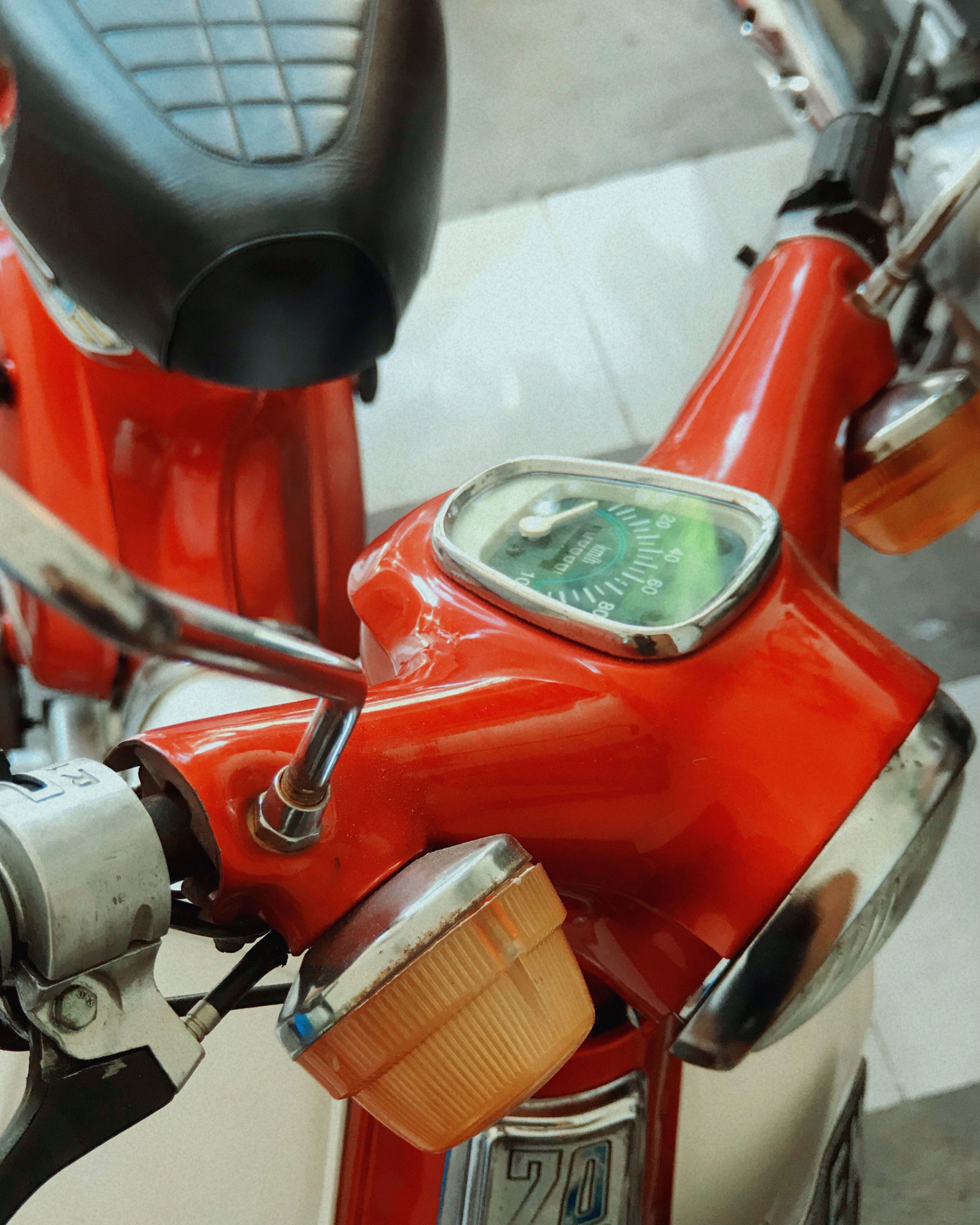 Detailed view of a classic red motorcycle featuring a vintage speedometer and retro design.