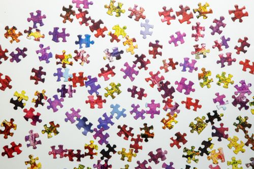 Free A vibrant collection of jigsaw puzzle pieces scattered randomly on a white surface, showcasing diverse colors and shapes. Stock Photo