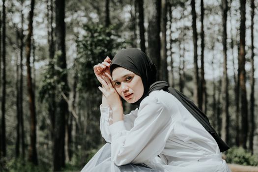 这幅肖像画描绘了一位戴头巾的妇女，背景是郁郁葱葱的森林，画面宁静安详