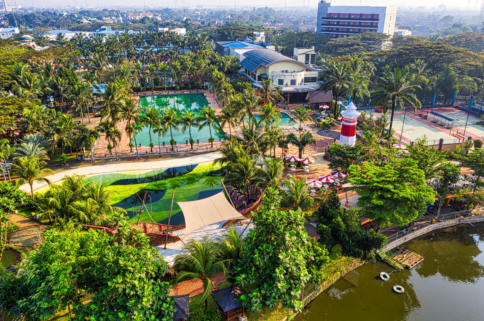 Aerial view of lush green resort with pools and palm trees in Banten, Indonesia, offering a tropical retreat.