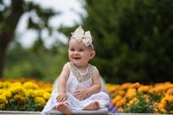 Smiling Little Baby Infant Sitting Outdoors near Flowers