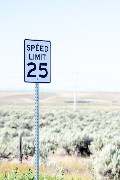 Free Road sign with speed limit inscription placed on way in countryside near hilly terrain on sunny day Stock Photo