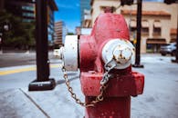 Typical red fire hydrant with rusty chain located on roadside in modern city on sunny day