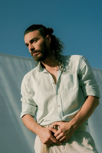 Serious thoughtful bearded male in classy outfit looking away under bright clear blue sky