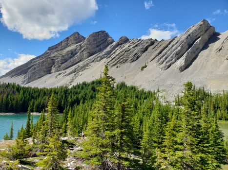 Explore the breathtaking landscape of Kananaskis, Alberta, showcasing rugged mountains, lush forests, and a serene lake.