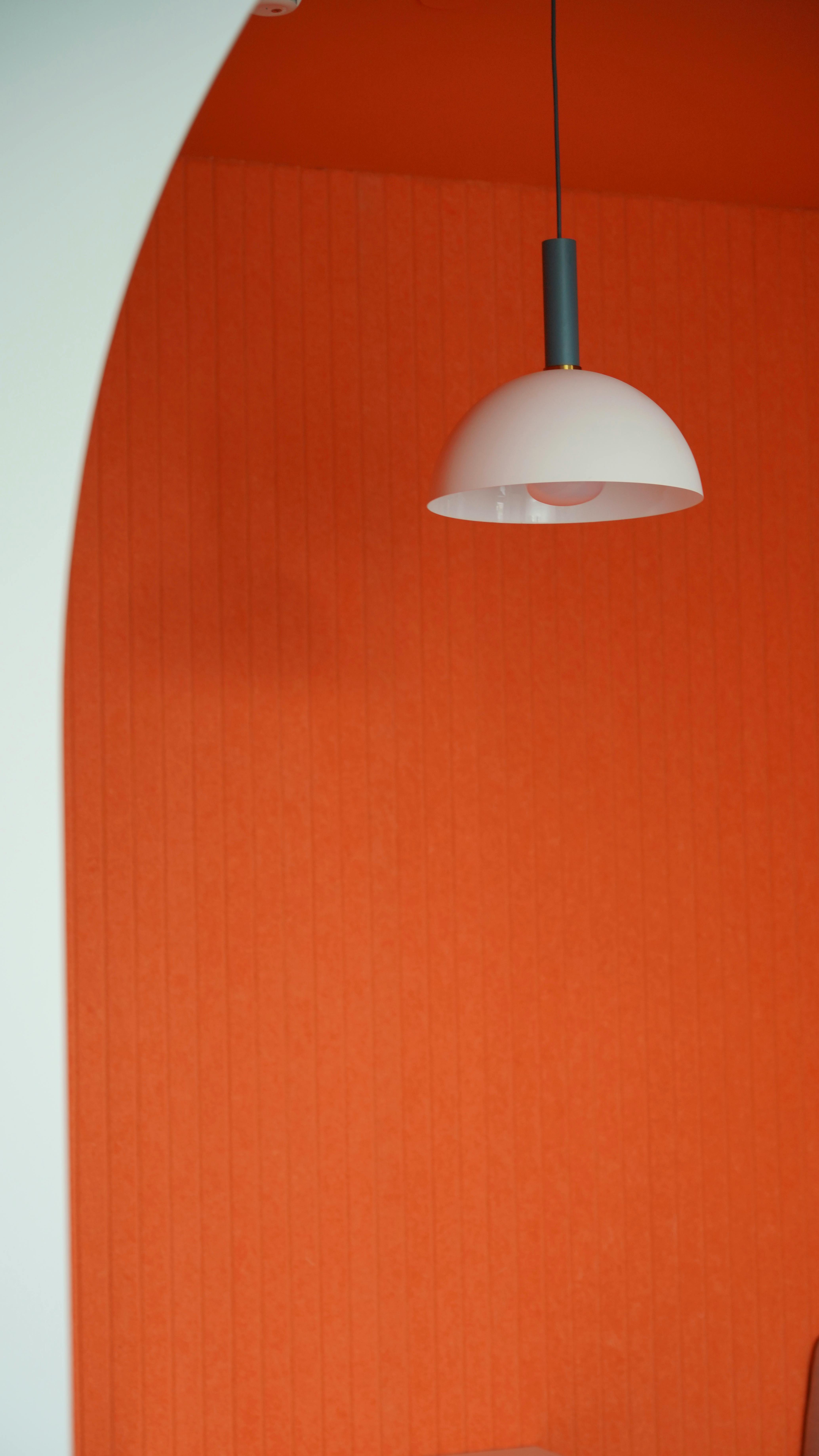 Modern minimalistic decor featuring an orange wall and white pendant lamp.