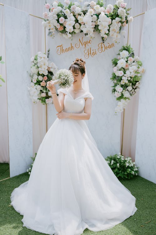 A Woman in White Wedding Dress Holding a Bouquet of Flowers