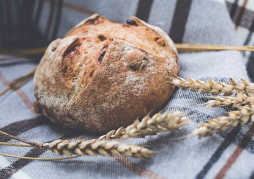 Free Artisan whole grain bread on a checkered cloth with wheat stalks, showcasing rustic food photography. Stock Photo