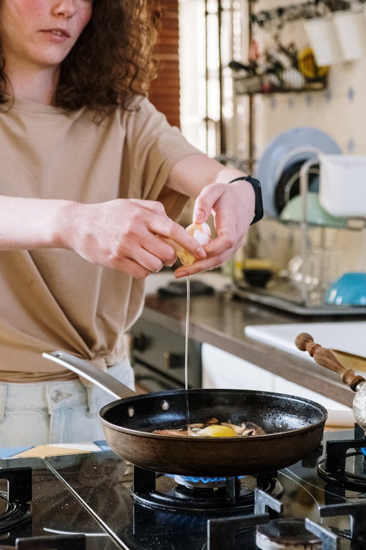 Person In Beige Shirt Cooking Eggs