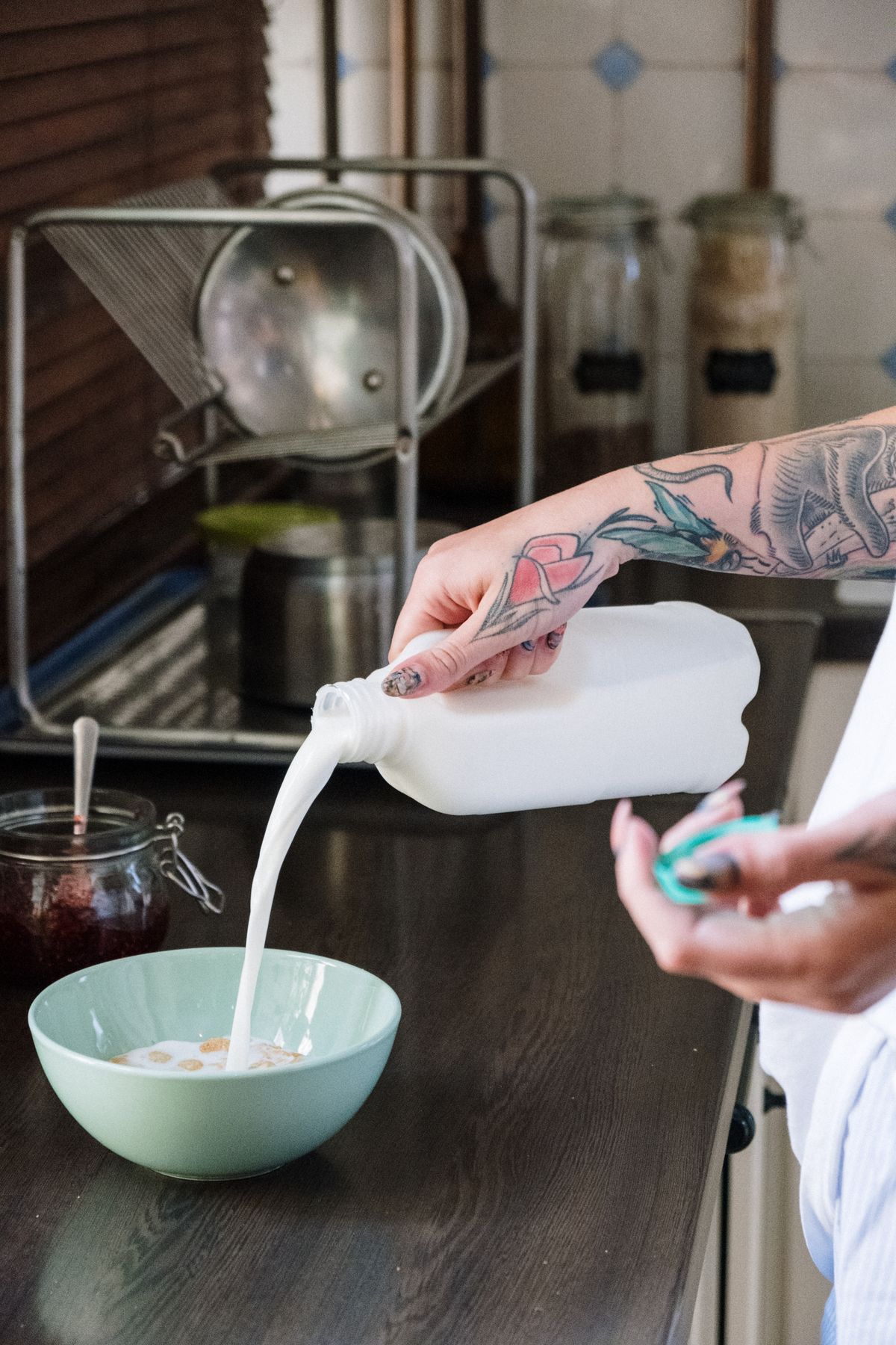 Milch wird in eine grüne Frühstücksschale gegossen