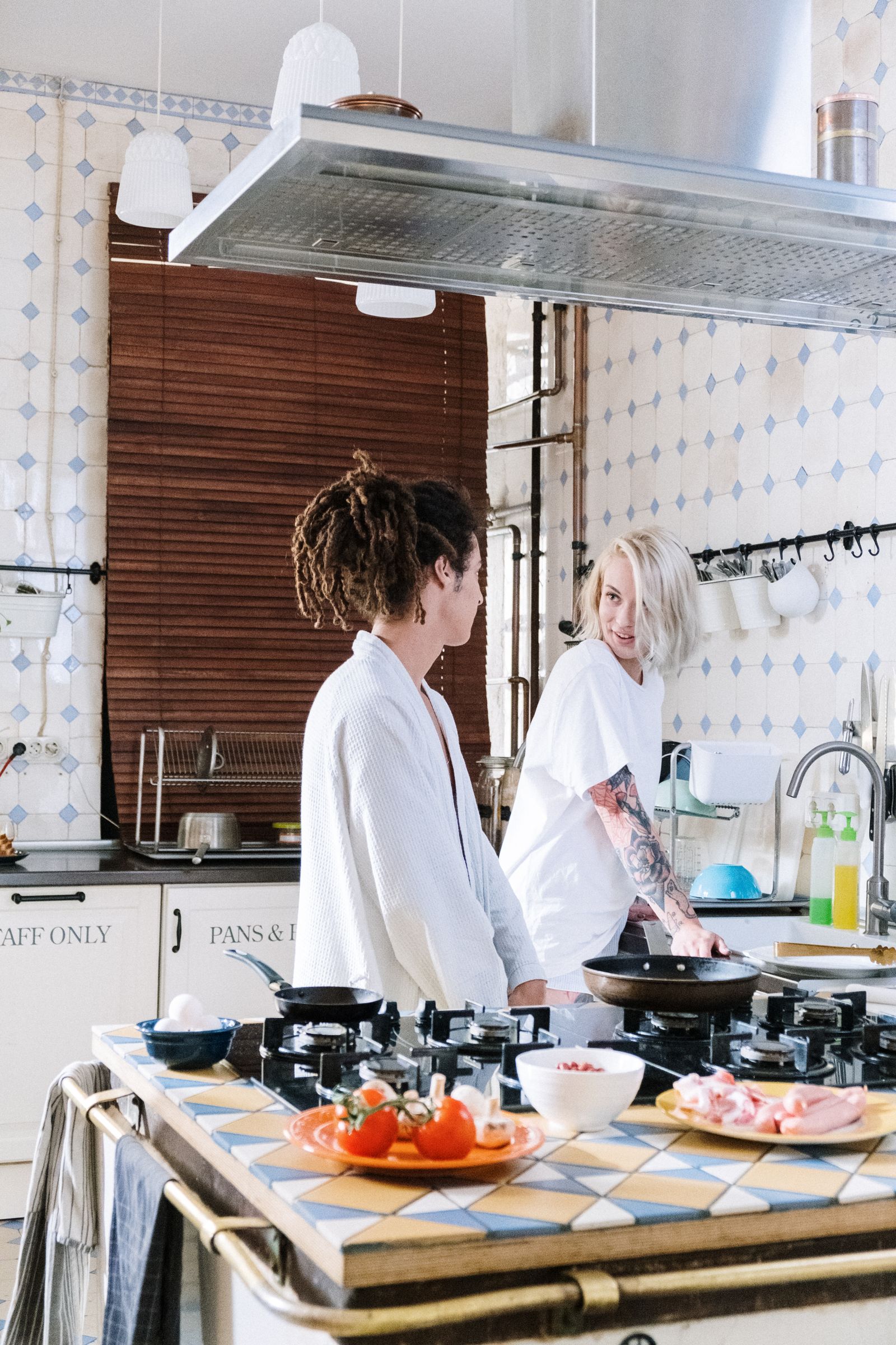 Two women conversing in a bright kitchen with food on the counter.