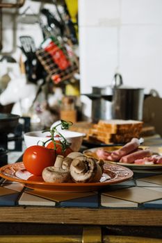 A close-up of fresh mushrooms and tomato on a kitchen counter.