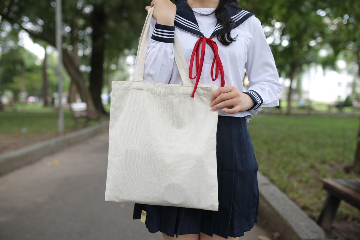 Student holding tote bag in park