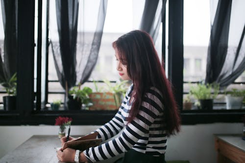 A Woman Writing on a Notebook