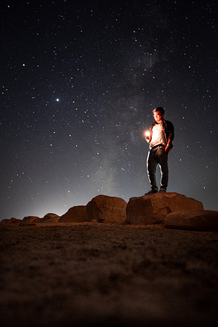 Man With Flashlight In Nature On Dark Night