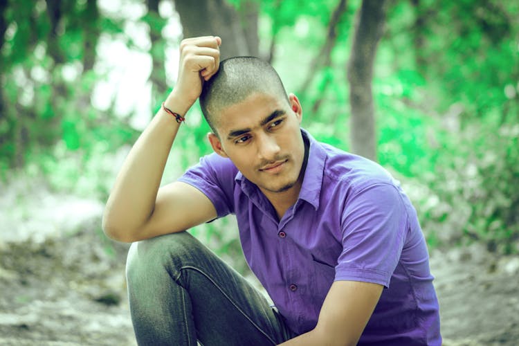 Man In Purple Polo Shirt And Denim Jeans Sitting On The Ground