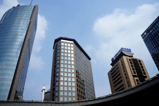 Low angle view of skyscrapers against a blue sky in a bustling cityscape.