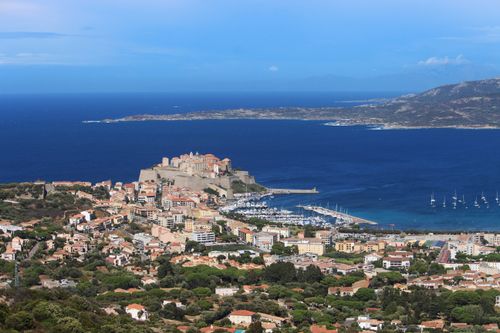 Free From above of coastal town located on coast among green trees near blue ocean in harbor in nature in sunlight Stock Photo