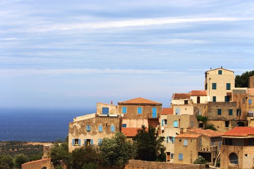 Free Coastal town with aged buildings with shabby walls located on hill near water against cloudy sky in nature in daytime Stock Photo