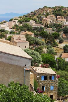 From above of town with typical houses located on hill with green vegetation against cloudless sky in nature in daytime