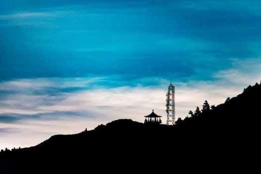 Silhouette of a communication tower and gazebo against a vibrant dusk sky.