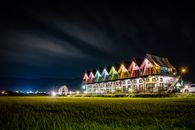 夜晚，一排充满活力的彩色房屋照亮了前景的草地