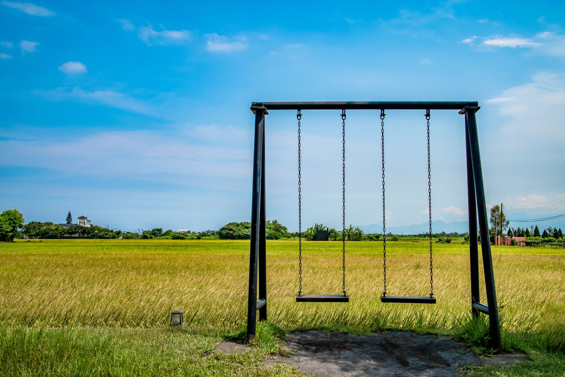 Peaceful rural setting with a swing set under a clear blue sky.
