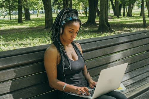 Woman Sitting on Bench While Using a Laptop
