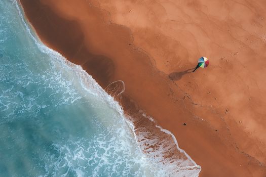 Top view of empty clean coastline washed by wavy foamy ocean in rays of sun