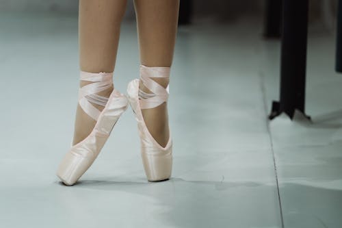 Crop faceless ballerina standing on toes