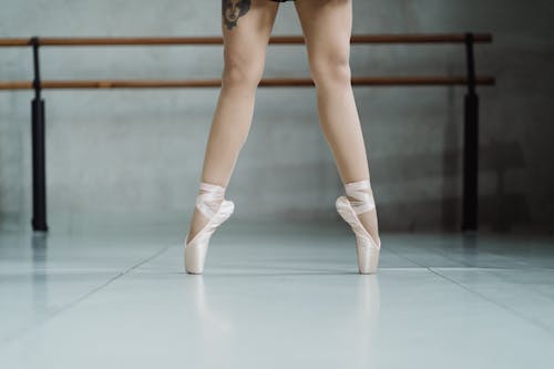 Crop unrecognizable ballerina tiptoeing in studio