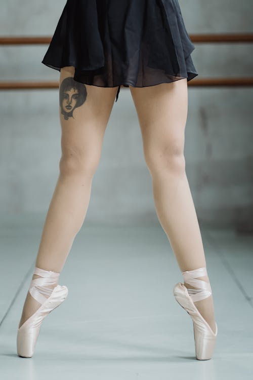 Free Crop faceless ballerina tiptoeing on pointe shoes in studio Stock Photo