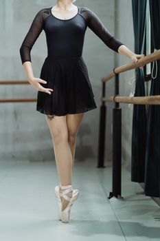 芭蕾舞演员身着黑色服装，在舞蹈室的栏杆上优雅地摆着姿势