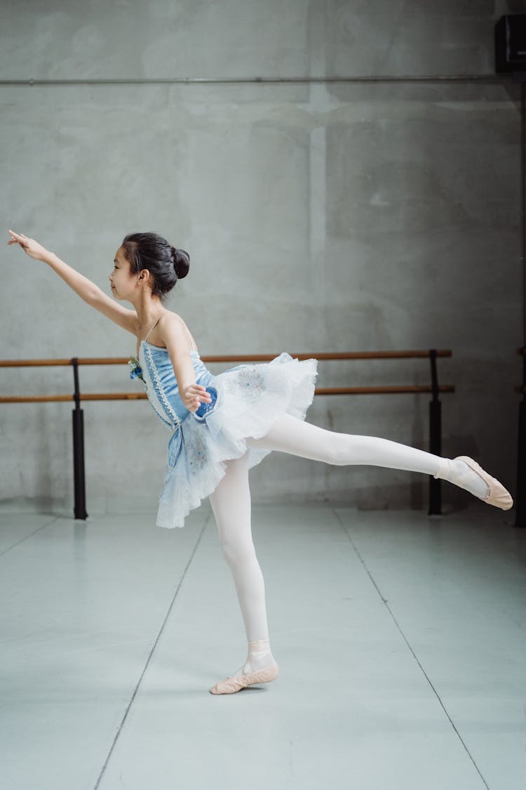 Graceful Ballerina Practicing Arabesque Balance Exercise In Ballet Studio