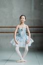 一位穿着蓝色芭蕾舞短裙的优雅年轻女孩正在演播室里练习芭蕾