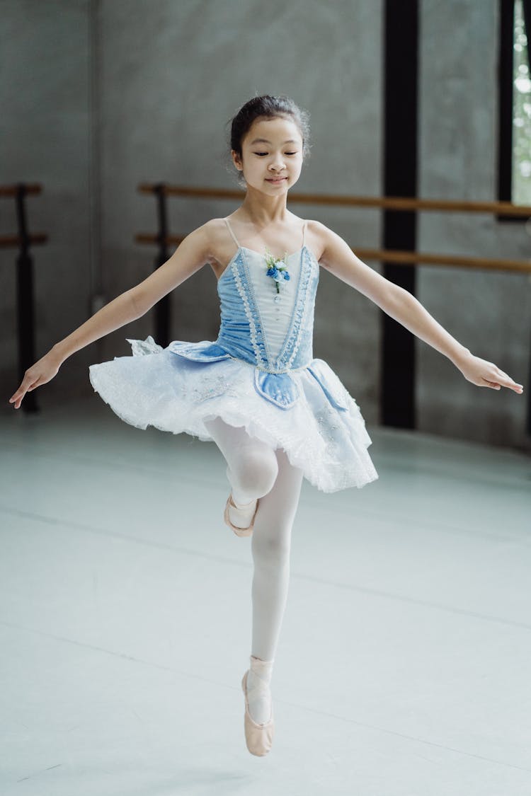 Positive Ballerina Girl Performing Dance Movement In Studio