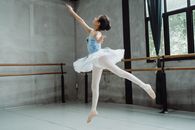 Ballerina girl performing ballet jump in studio