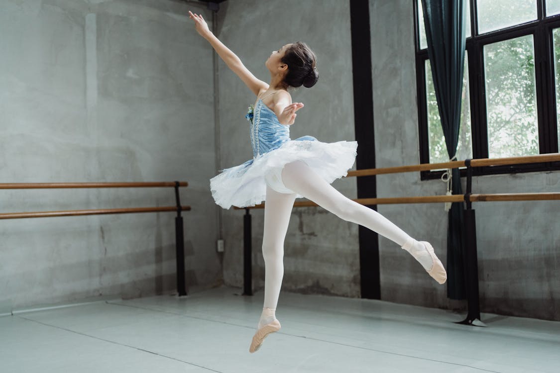 Free Ballerina girl performing ballet jump in studio Stock Photo